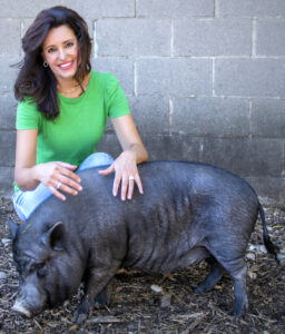 Suzana Gartner with a black pig at a farm